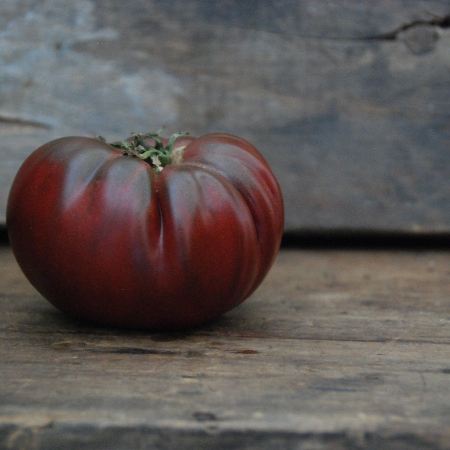 Black tomato on a wooden surface with a rustic background