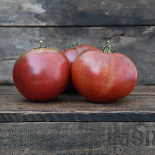 three brown tomatoes on a wooden surface