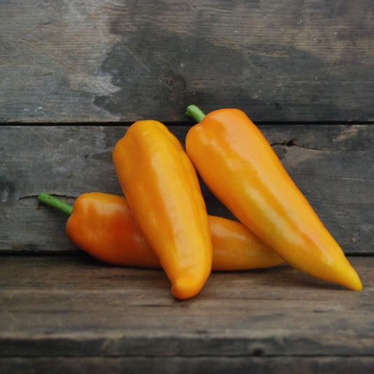 Three yellow peppers on a wooden surface