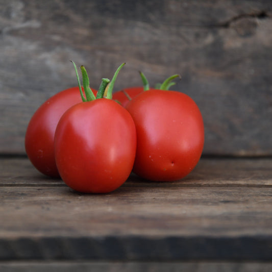 four roma tomatoes on a wooden surface
