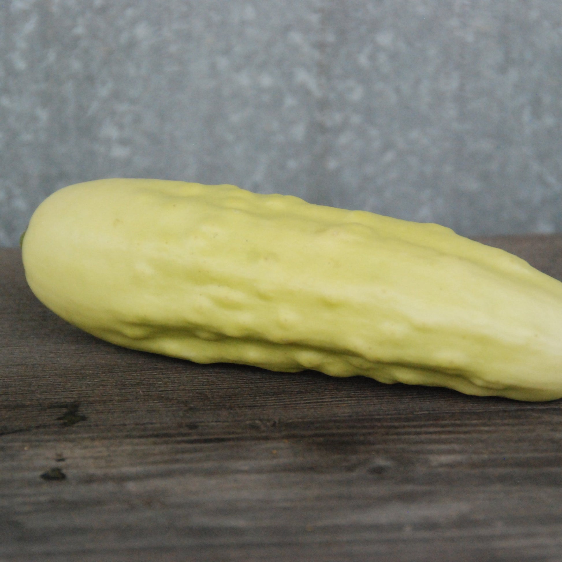 Silver slicer cucumber on a wooden surface with a gray background