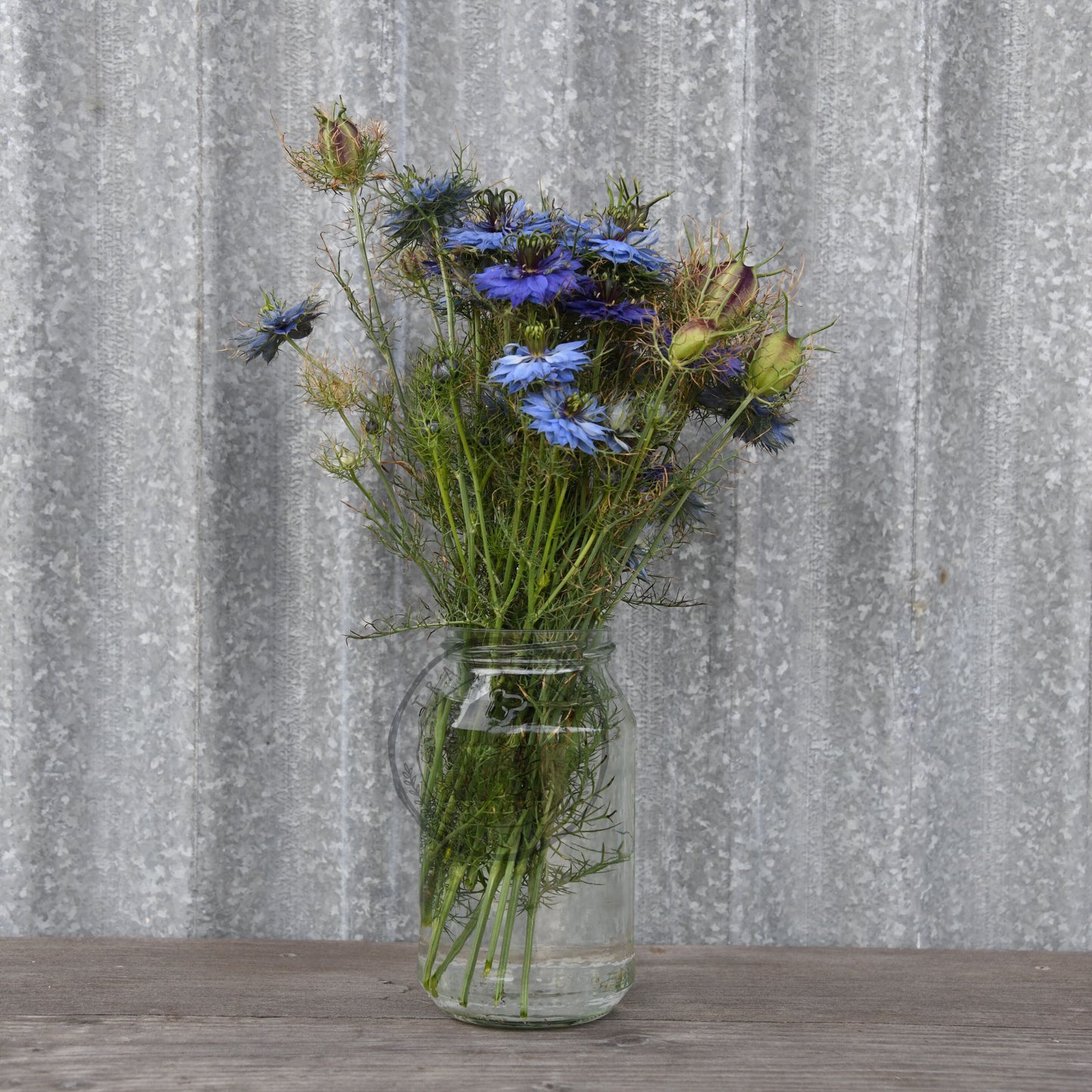 Vase with wildflowers on a wooden surface against a textured gray wall