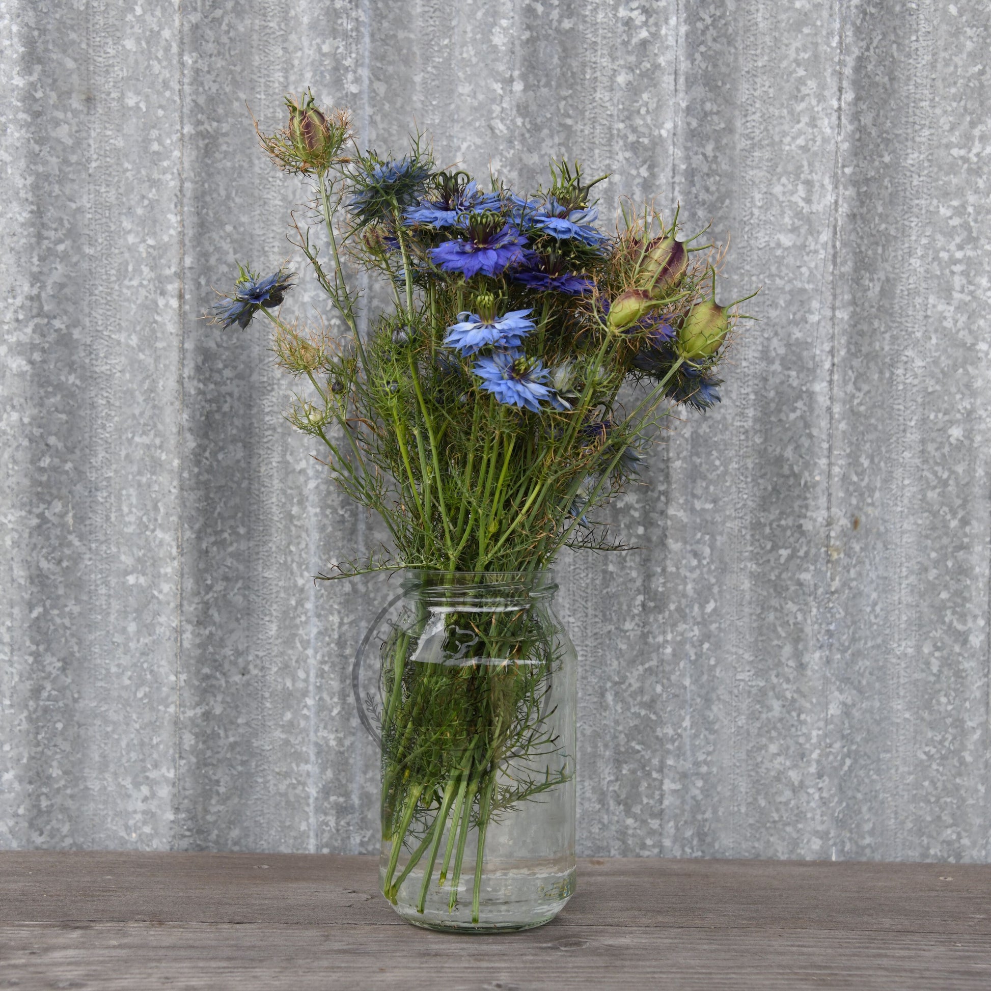 Vase with wildflowers on a wooden surface against a textured gray wall