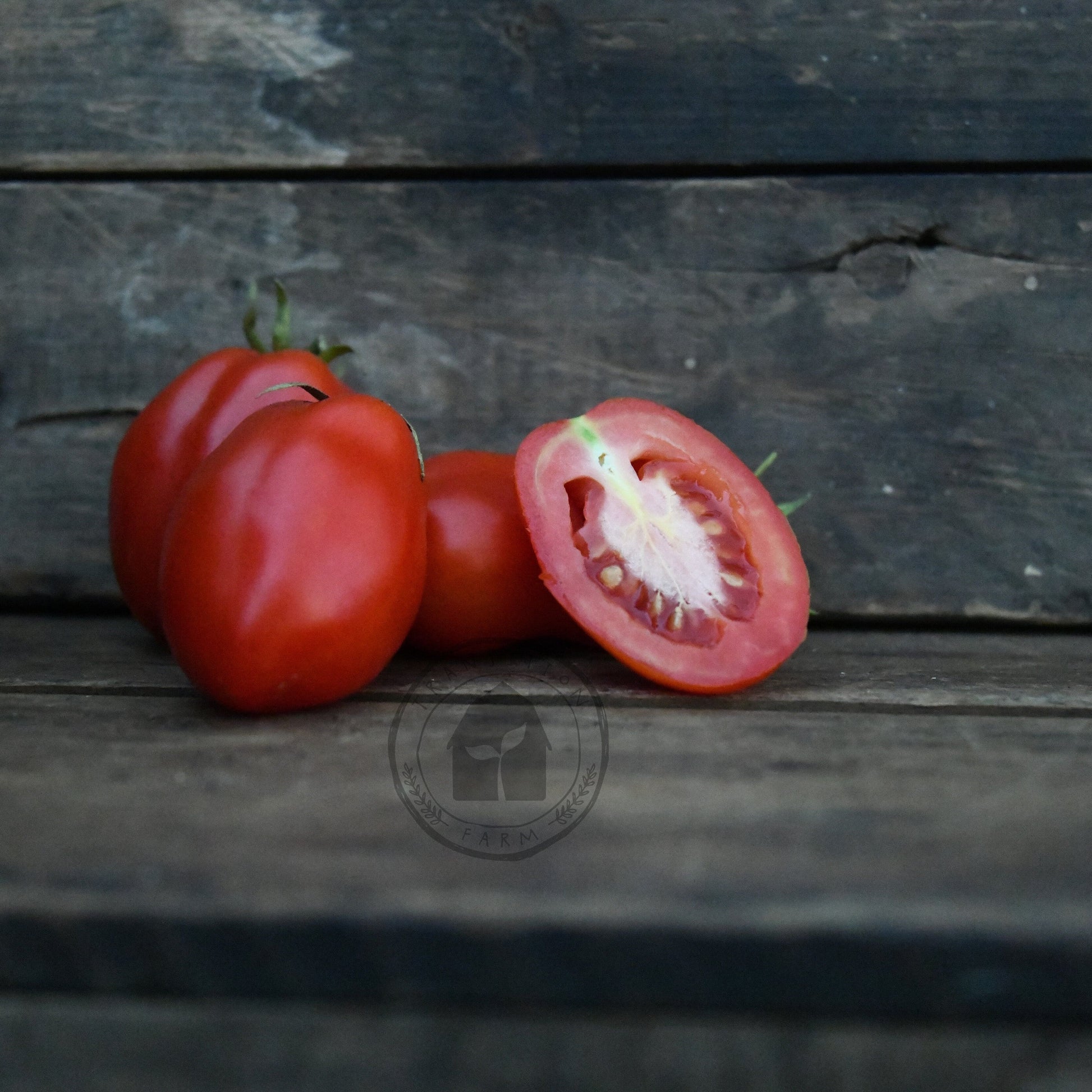 Tomatoes on a wooden surface with one sliced open