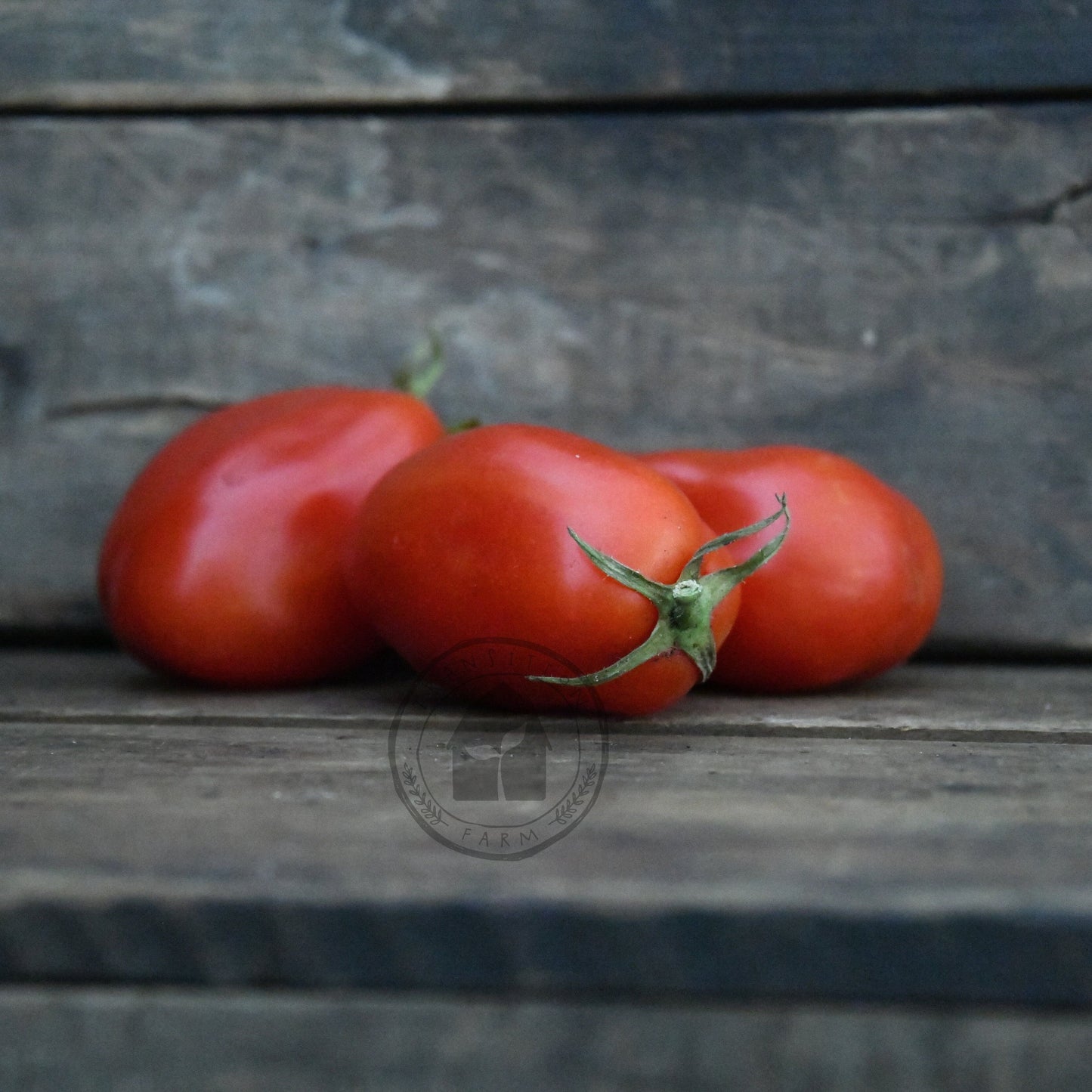 Three red tomatoes on a wooden surface