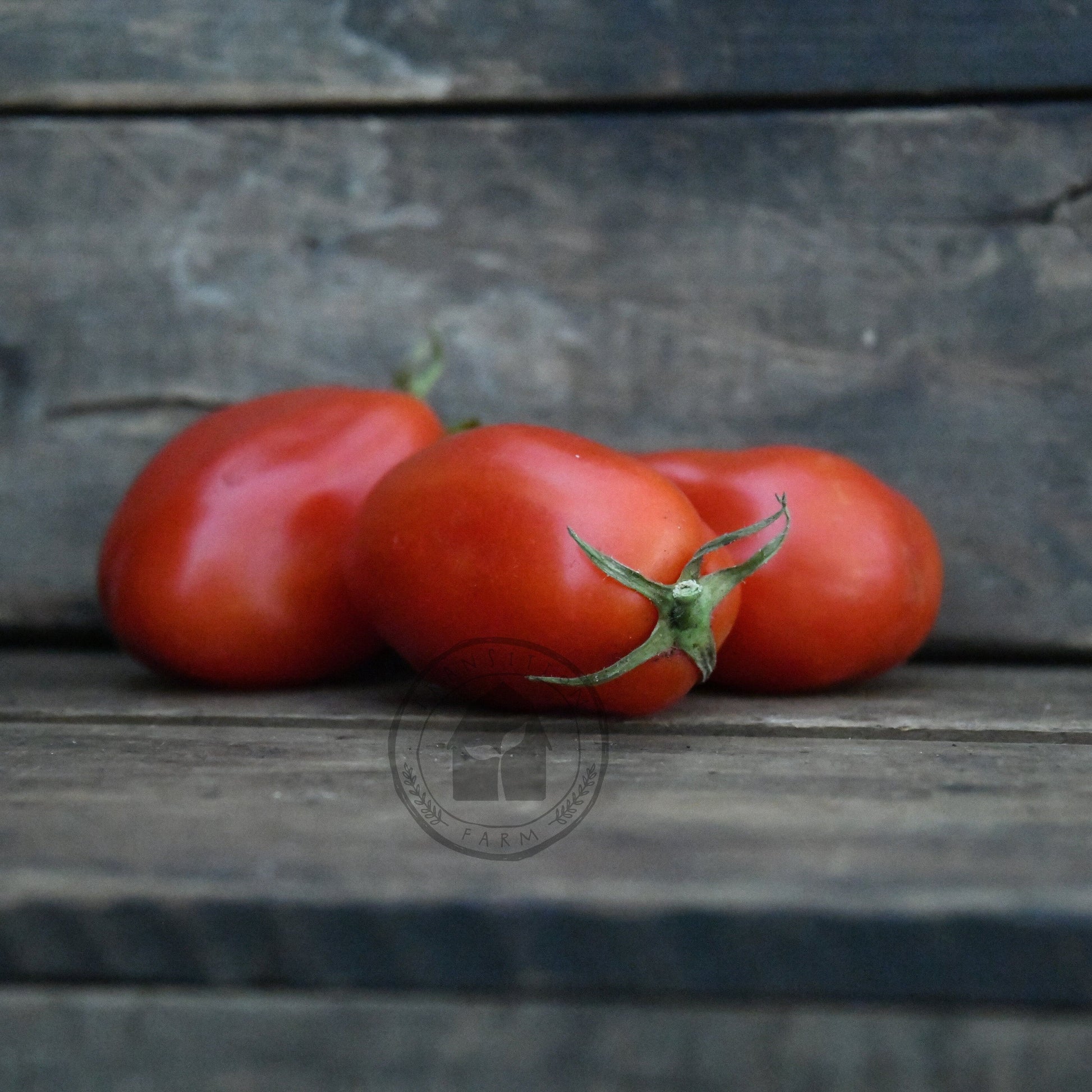 Three red tomatoes on a wooden surface