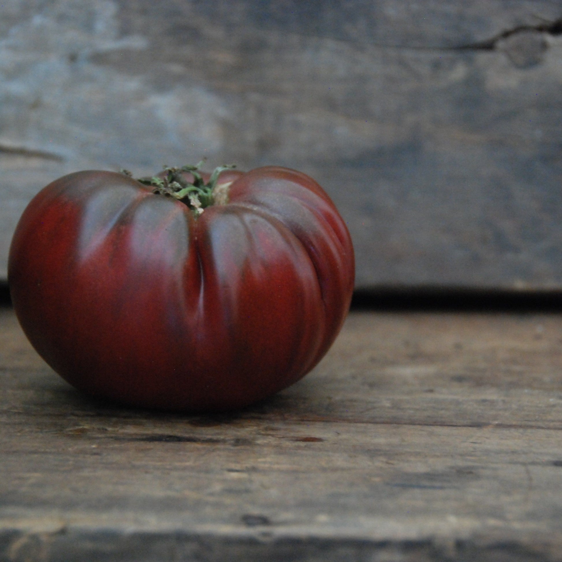 Black tomato on a wooden surface with a rustic background