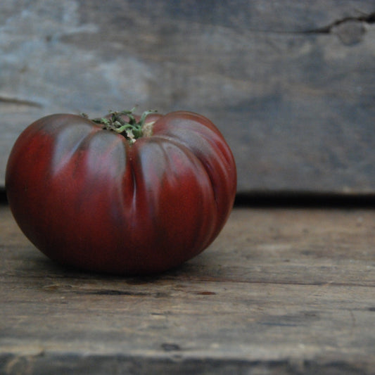 Black tomato on a wooden surface with a rustic background