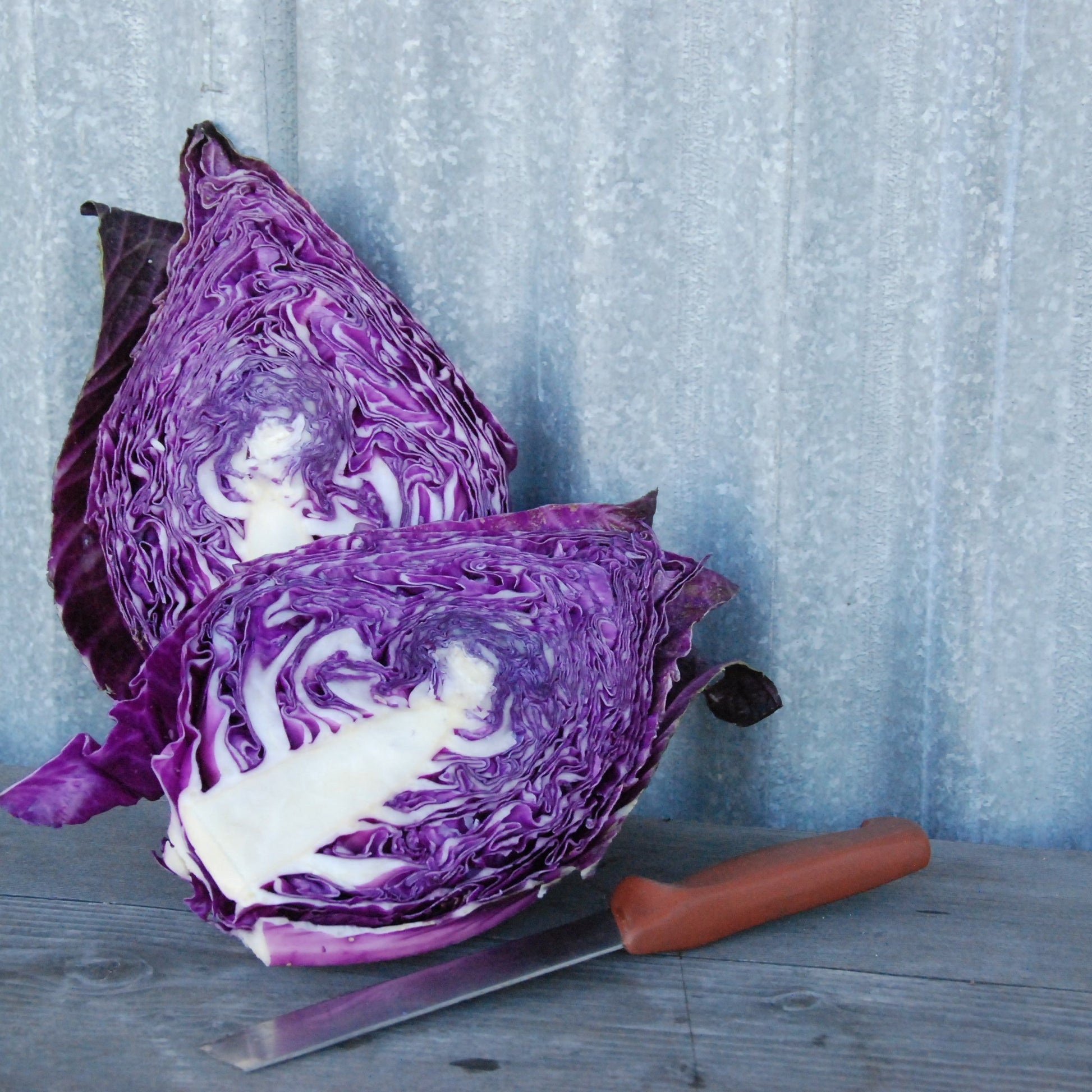 Purple cabbage cut in half with a knife on a wooden surface