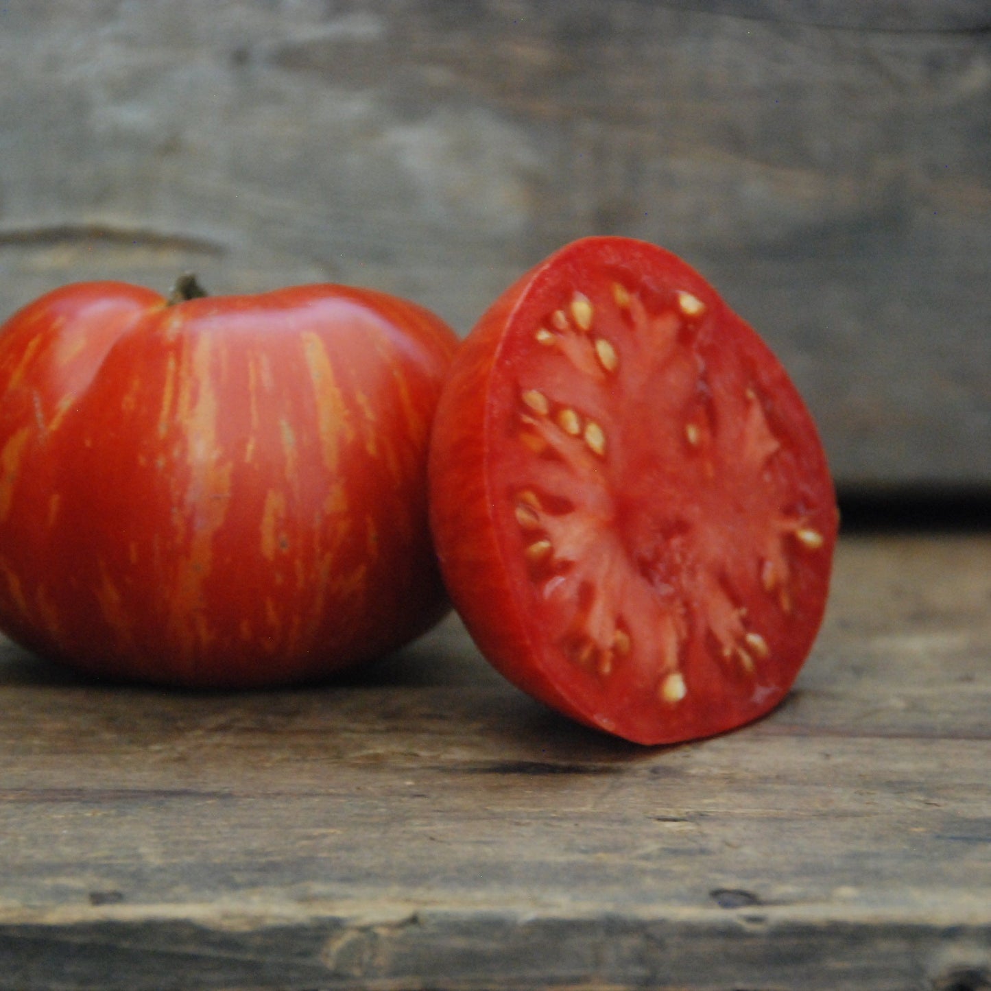 two tomatoes on a wooden surface