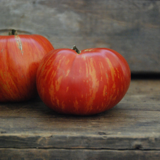 two tomatoes on a wooden surface