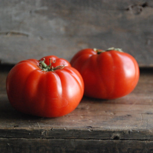 two red tomatoes on a wooden surface