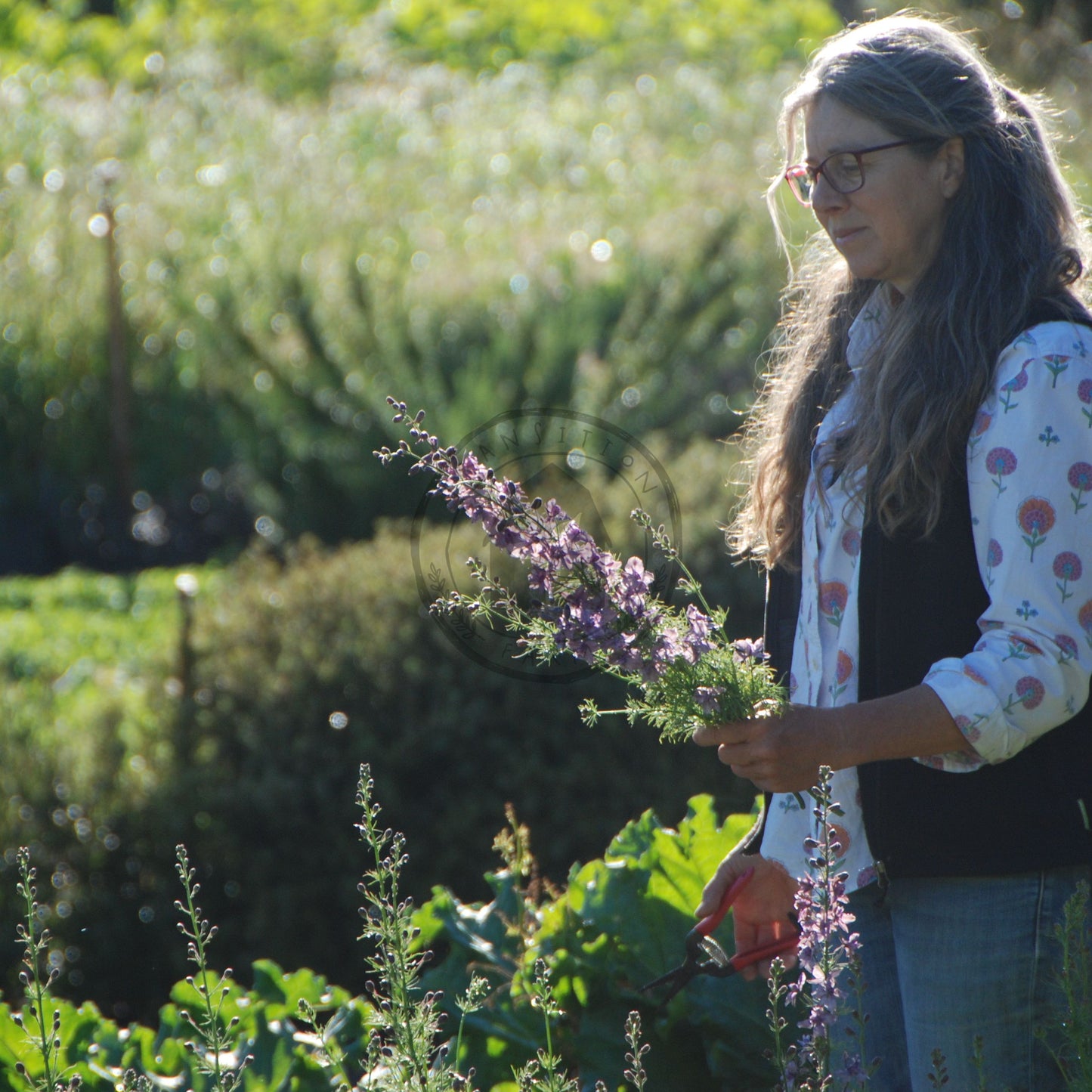 Woman holding a bundle of flowers in a field