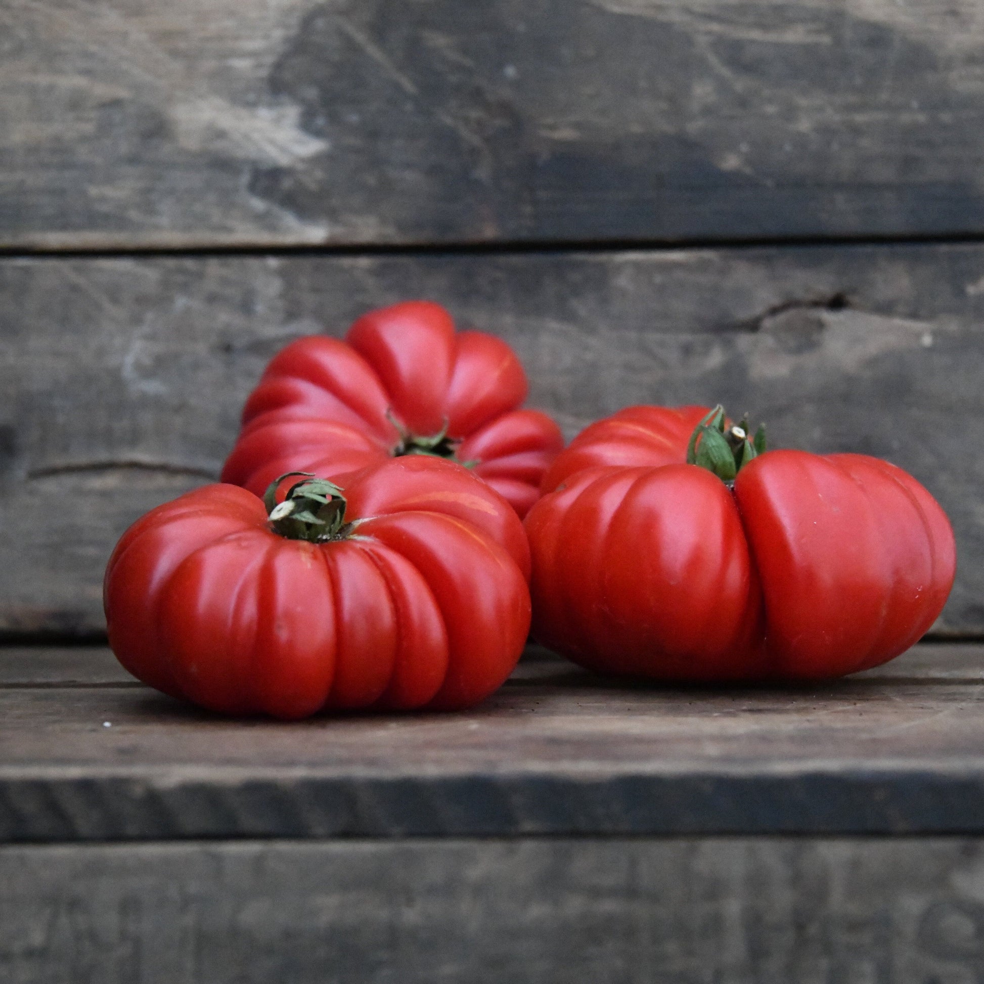 Red tomatoes on a wooden surface with a rustic background